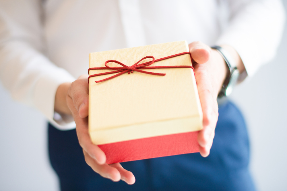 closeup-person-giving-big-gift-box-with-bow